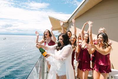 Bride opening champagne with bridal party cheering