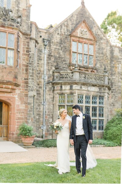 Sam and Petie,  owners of The Tuckers Photography, walk hand in hand in front of a waterfall in Iceland.