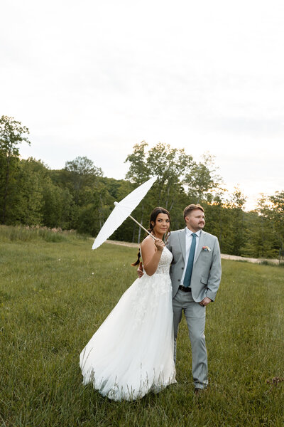 Bride and groom sharing a joyful moment under a stylish umbrella during their outdoor Kentucky wedding, photographed by Abby Dutra.