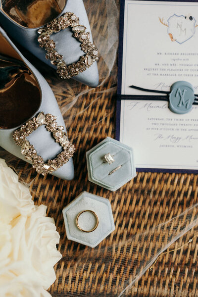 flatlay of bridal shoes, engagement ring and wedding invitation