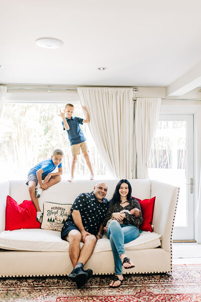 older boys playing in thier home with a newborn baby in mom's arms.