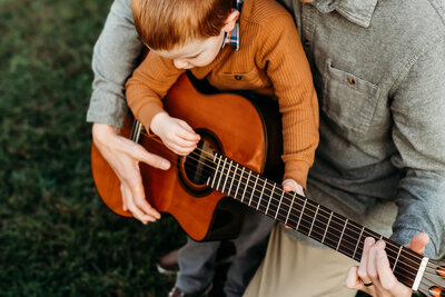 young boy playing guitar with dad by lancaster pa family photographer
