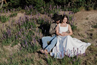 Bride and groom sit in wildflower patch at Sapphire Point Overlook.