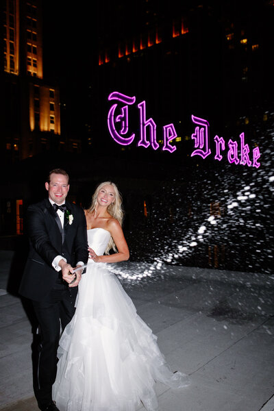 Bride and groom spray a bottle of champagne after their wedding on the rooftop of the Drake Hotel in Chicago