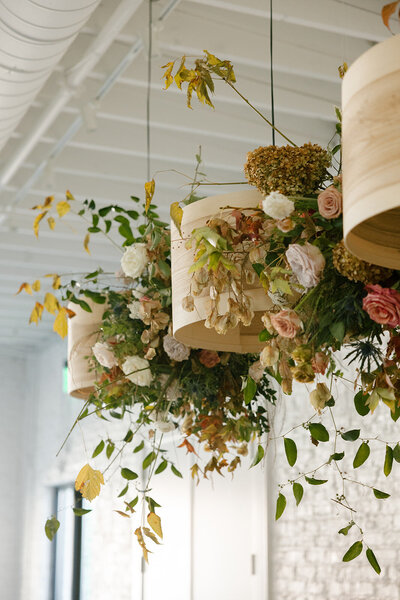 Floral Chandelier hanging clouds accent fall wedding reception in Raleigh, NC with roses, hydrangeas, and fall branches in colors of mauve, copper, cream, dusty pink, and green. Design by Rosemary and Finch in Nashville, TN.