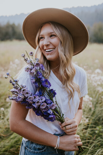 Young woman holds flowers and smiles during sunset.