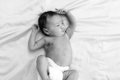 Baby stretched in bed during newborn photography session in Elmhurst, IL