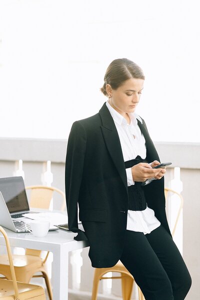 woman in a business outfit texting on her phone