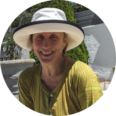 The host, Barbara smiling while sitting outside wearing a hat