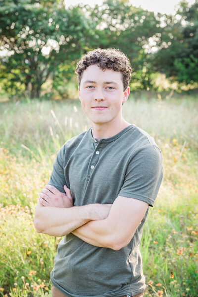 Man posting with arms crossed in a field