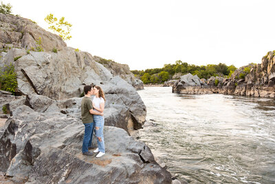 Couple standing on rocks kissing at Great Falls, Virginia
