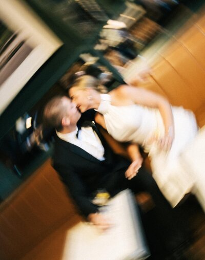 A bride and groom walk across a lawn in a documentary-style black and white photo.