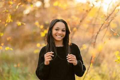 girl in black sweater playing with her hair in the fall woods
