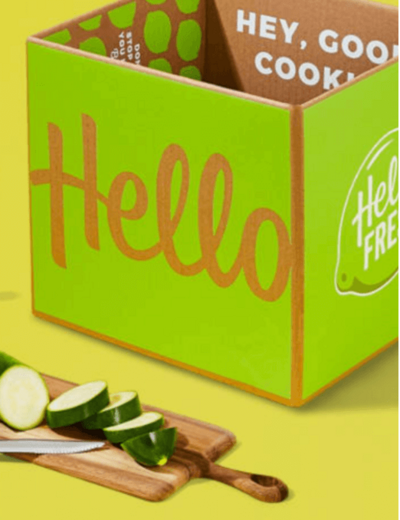 Hello Fresh box with a cutting board and fresh vegetables