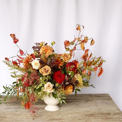 An autumn-inspired floral arrangement in a white vase.