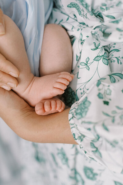  Richmond Newborn Photographer | Closeup photo of a newborn baby's feet as his mother holds him close, wearing a green and blue floral print dress by Jacqueline Aimee Portraits