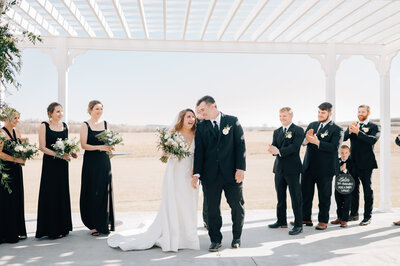 Bride and groom smile at each other as they walk down the aisle after getting married at a venue in Iowa. Photo by Anna Brace, who specializes in Wedding Photography in Des Moines.