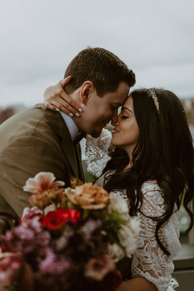 bride in luxurious lace wedding gown posed by window