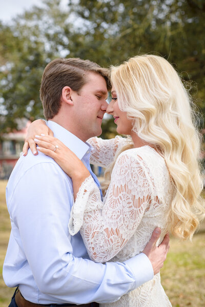 Engaged couple in the park at sunset, with the groom lifting the bride under oak trees with hanging moss