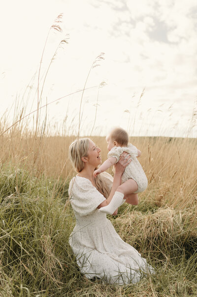 Mother plays with her baby in a field