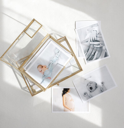 Flat lay of printed newborn and maternity photographs in a gold glass keepsake box, showcasing luxury photography artwork by Little Palm Photography Studio in Northern California.
