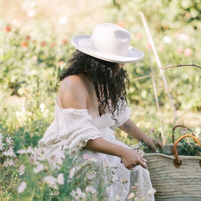Natalia picking flowers into a basket in a garden in Belgium, living her best life.