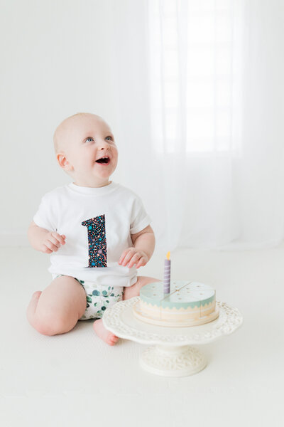 a wicker bassinet stands in the corner of a beautiful white photography studio next to pampas grass