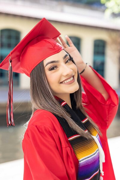 Senior pictures of a proud graduate wearing a red gown and cap at her university in Dallas, TX, celebrating her achievement