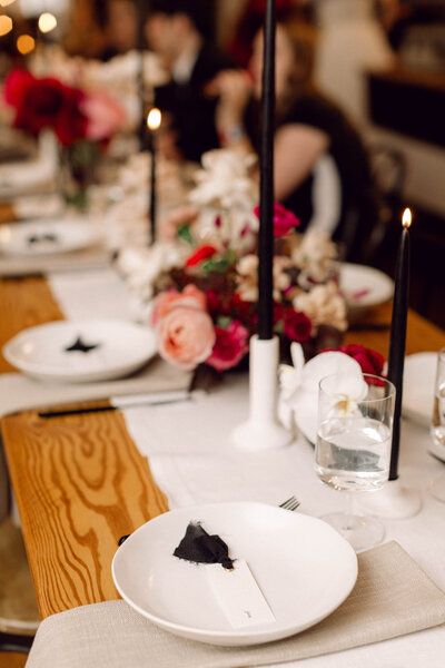 Close-up of elegant wedding reception plates and floral centerpieces with soft candlelight glowing in the background at an intimate backyard wedding in Richmond, Virginia