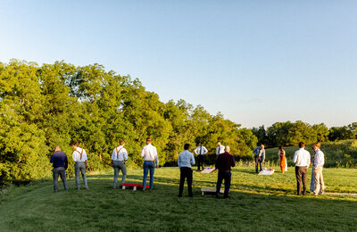 Photo of wedding guests playing cornhole in outdoor ceremony area at The Eloise
