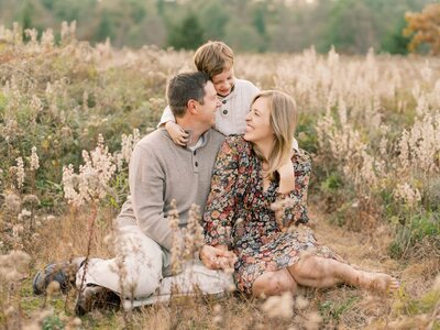 Family of three snuggling during a fall session in saco maine