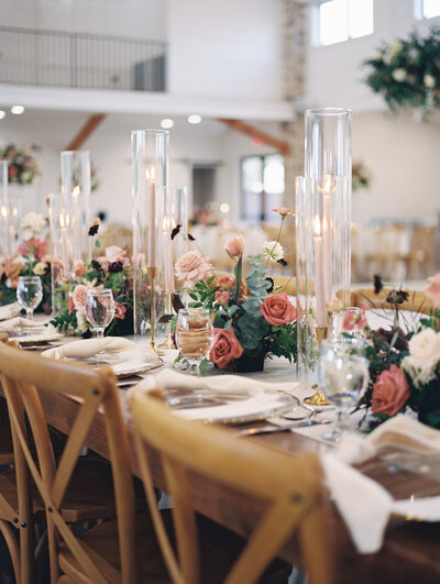 Reception table setting decorated with candles and pink and green floral arrangements