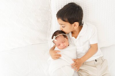 kid kissing newborn baby sibling taken by Boston Newborn Photography
