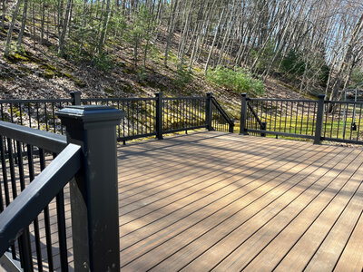 A dark natural wood looking composite deck with black railings