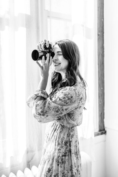 Black and white photo of photographer looking at the back of her camera.