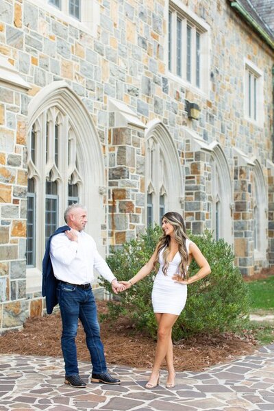 engaged couple holding hands in front of a stone building
