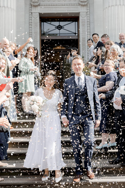 Just married couple walking down the stairs with confetti being thrown.