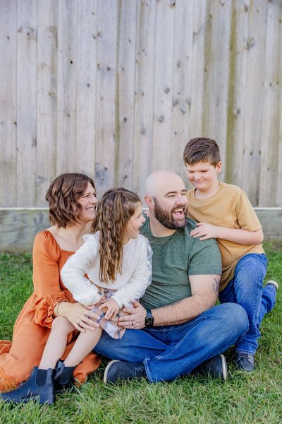 Family at Centennial Pines Tree Farm sitting and laughing together. 