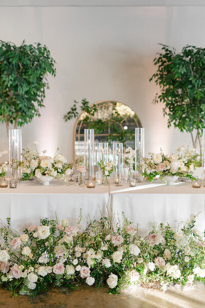 Low floral centerpieces for elegant wedding overflowing with white garden roses, ranunculus, butterfly ranunculus, scabiosa, lisianthus, sweet peas, and natural dark greenery. Floral hues of white, cream, and blush. Designed by Rosemary and Finch in Nashville, TN