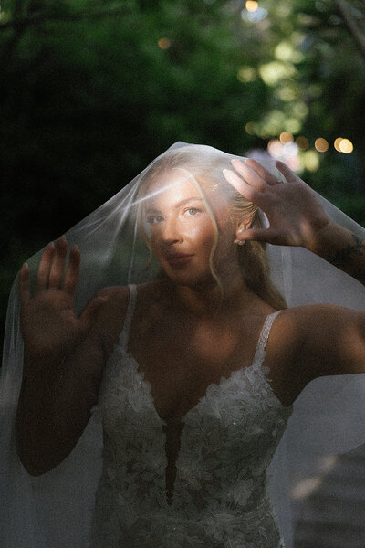 Bride in harsh light while bride holds her veil 