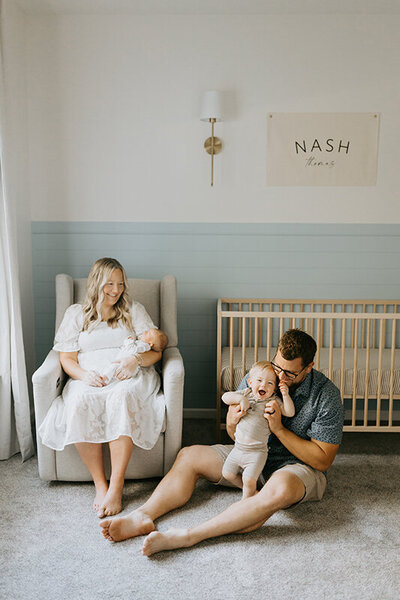 A lifestyle newborn photographer captures dad, mom, and big brother in the baby's Lafayette, Indiana nursery.