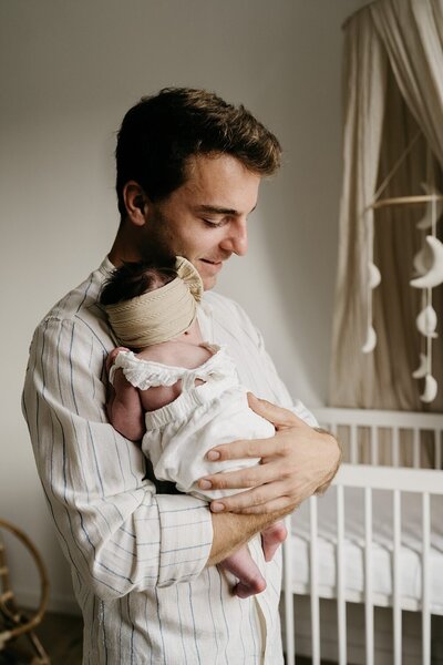 baby in de armen van papa op de babykamer