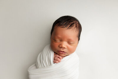 Newborn baby boy wrapped in white.