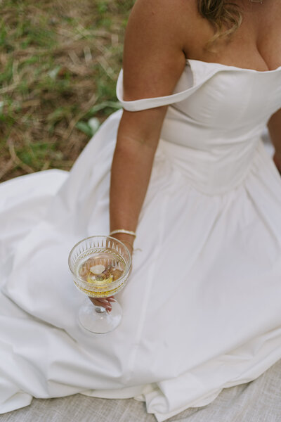 Bride holding a champagne glass sitting down.