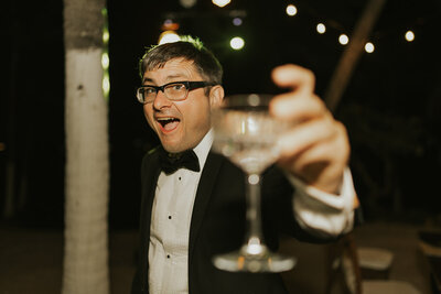 man in tux (Dean) cheers's a glass at the camera