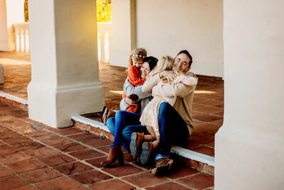 Family photographer, a mom and dad hug their daughters