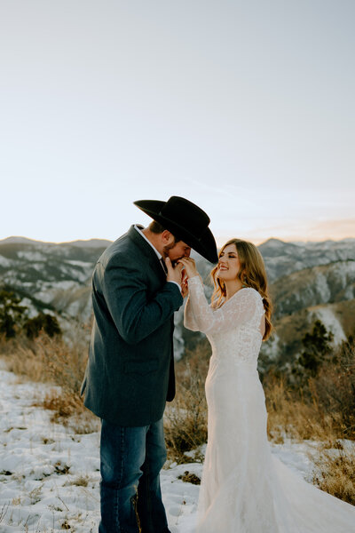 groom kissing his brides hand as they enjoy their elopement in the mountains