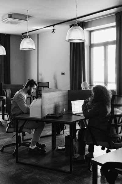 Black and white photo of people working at desks in shared office