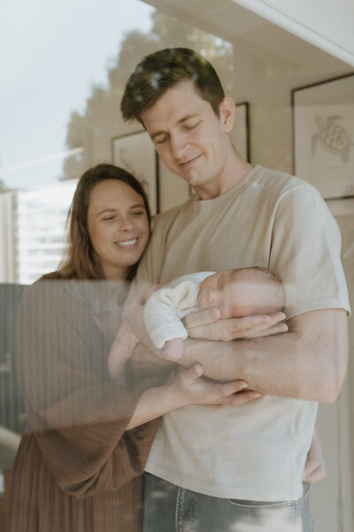 Looking through the window of a Brisbane home to see two new parents doting on their newborn son.
