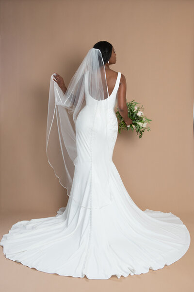 Bride wearing a floor length veil with ribbon edge and holding a white and blush bouquet